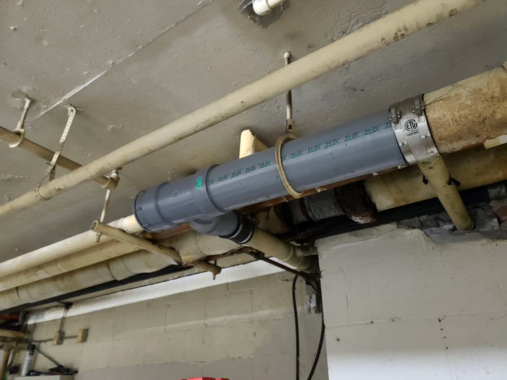 New PVC drain line run along a basement ceiling